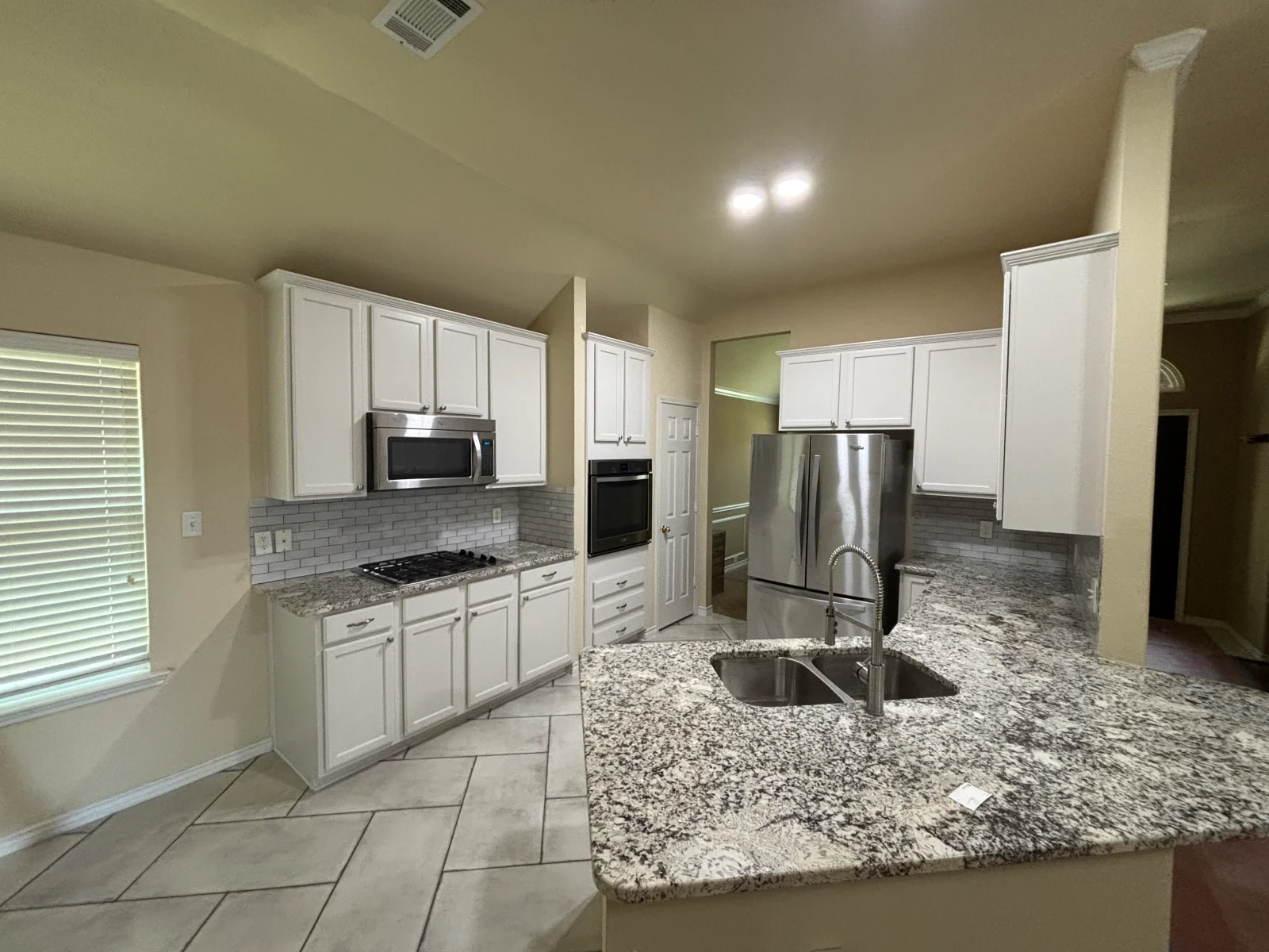 White painted kitchen cabinets with granite counters and stainless steel appliances