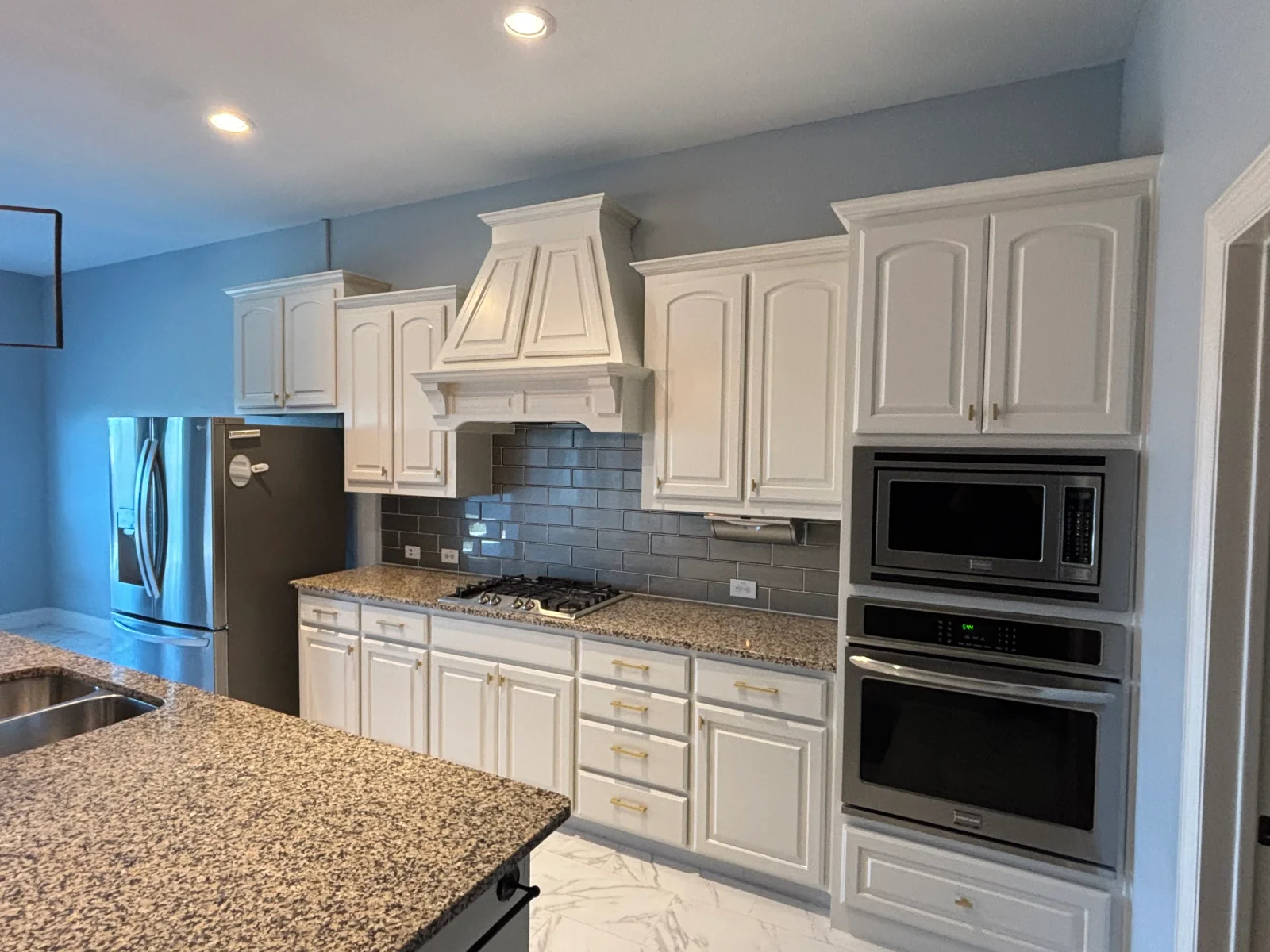 White painted kitchen cabinets with gray subway tile backsplash and blue accent walls