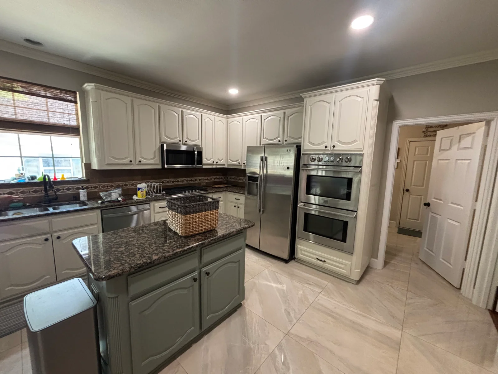 Cream painted kitchen cabinets with granite counters and stainless steel appliances
