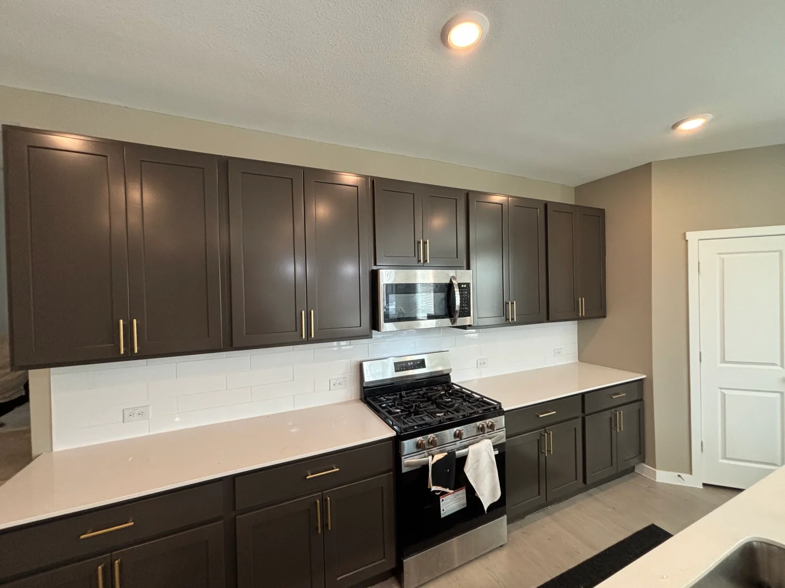 Dark brown painted kitchen cabinets with white subway tile backsplash and recessed lighting