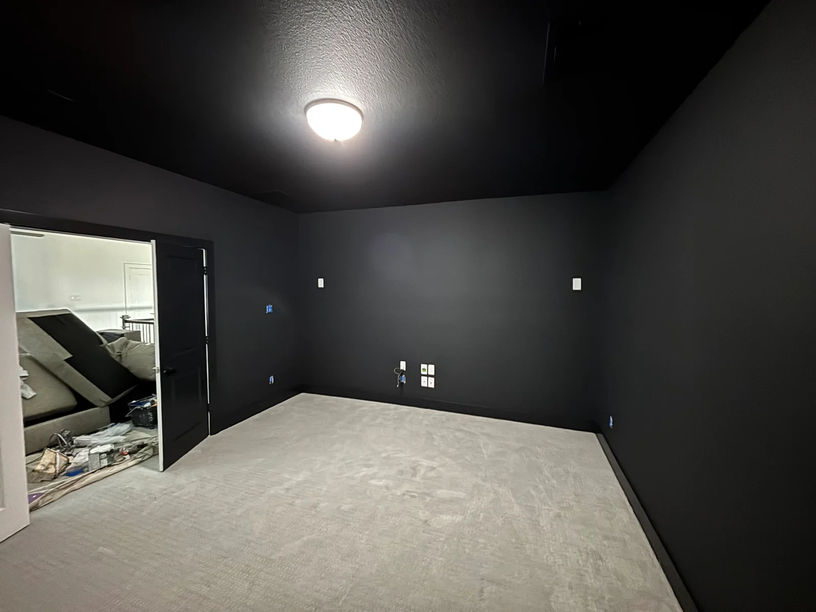 Black painted walls and textured ceiling with recessed light fixture and electrical outlets in finished interior room